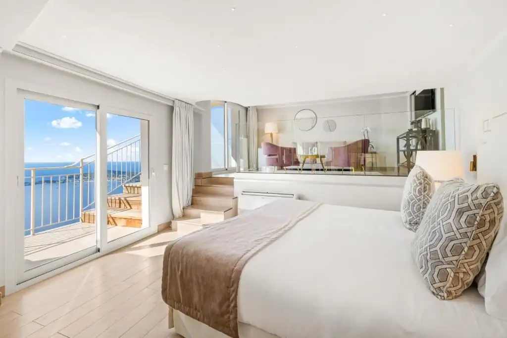 Elegant bedroom suite with private balcony and sea view at Château de la Chèvre d'Or in Èze