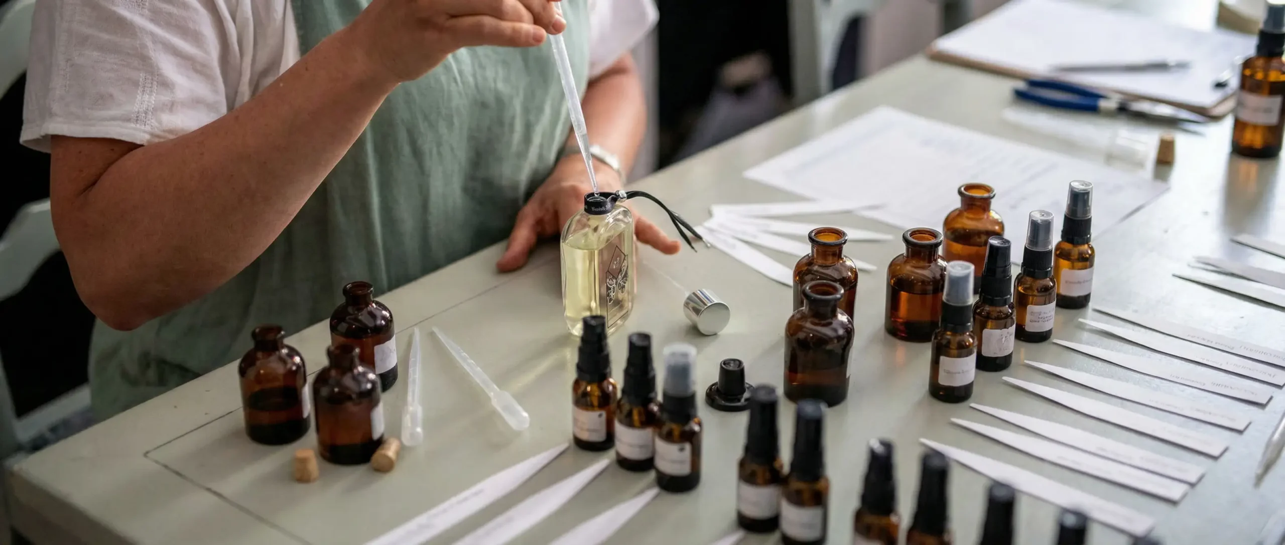 Hands creating perfume in a fragrance workshop with glass bottles and essences