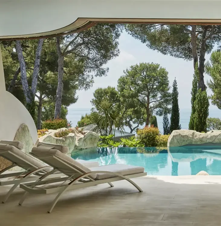Outdoor pool surrounded by lush gardens and sun loungers at Grand-Hôtel du Cap-Ferrat