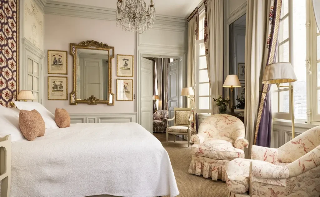 Luxurious historic suite interior featuring antique furnishings, a crystal chandelier, and large sunlit windows