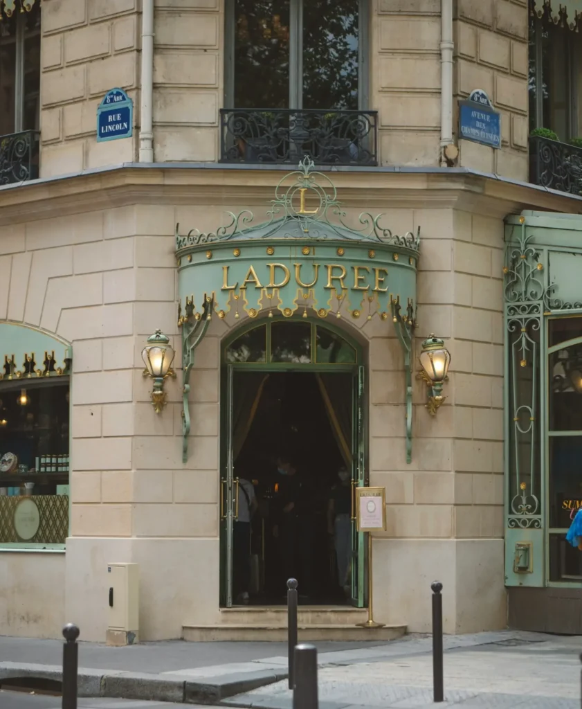 Wide shot of a Ladurée pastry shop entrance on a Parisian street corner