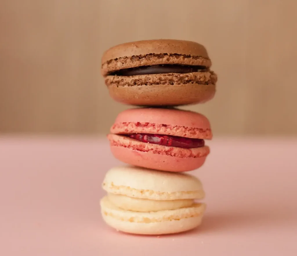 The Best Macarons in Paris - A vertical tower of four macarons in chocolate, pink, and cream flavors