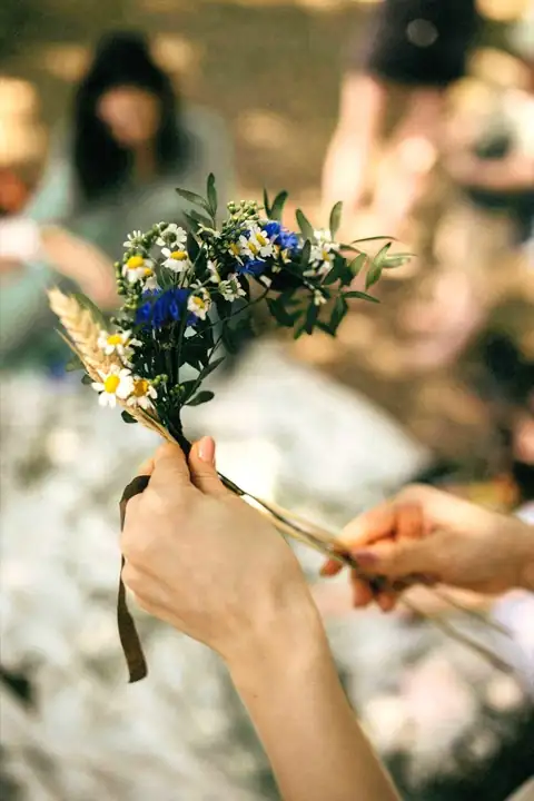 Hands arranging blue and green wildflowers into a botanical crown in Provence