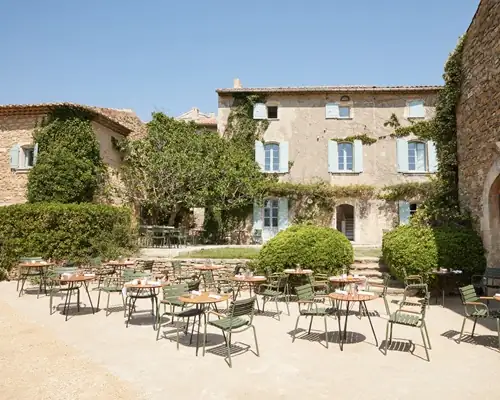Historic stone bastide with ivy-covered facade and outdoor terrace dining in Provence