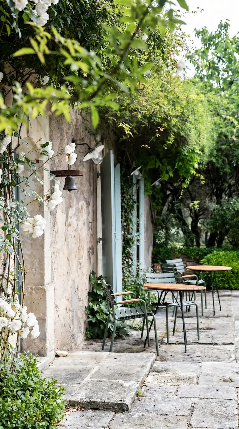 Sunlit stone courtyard with wrought iron bistro table and climbing greenery at a Provence luxury retreat