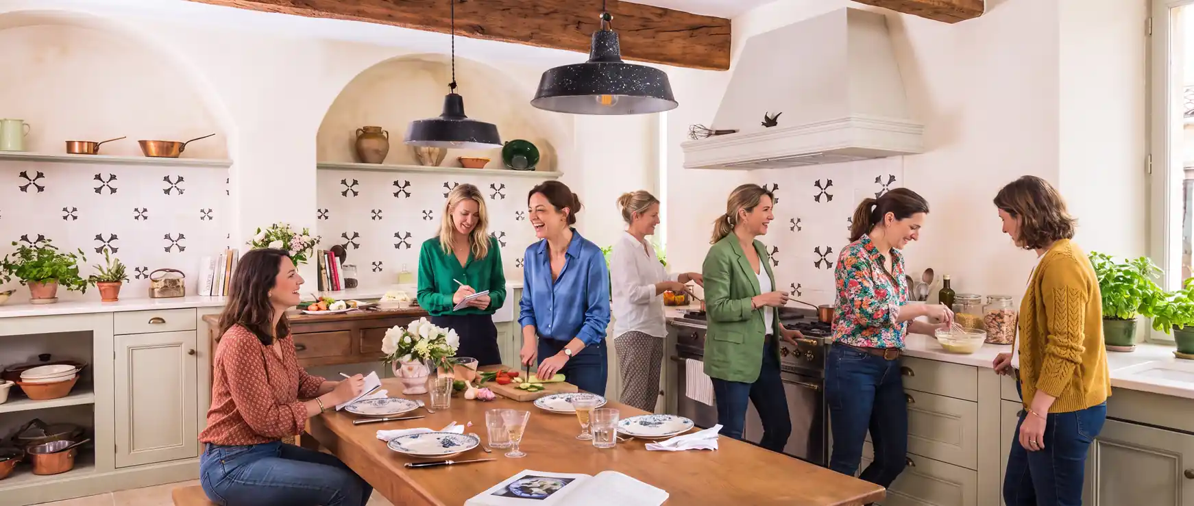 Group of women gathered in a Provençal kitchen preparing a meal together during a wellness retreat cooking class