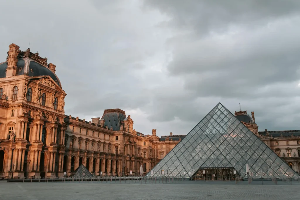 Paris trip with friends, The glass pyramid of the Louvre Museum courtyard under a cloudy Paris sky